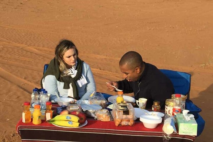 Savor a delightful breakfast amid the stunning red dunes enjoying a unique blend of culture and nature while exploring Dubai's desert landscapes together.